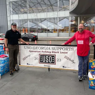 Two Pond employees standing in front of USO sign